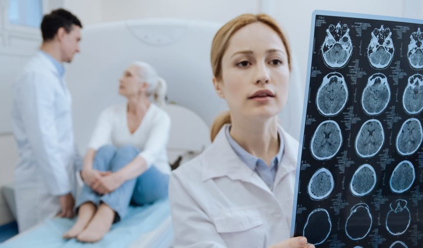 Doctor looking at brain scan results with patient in background