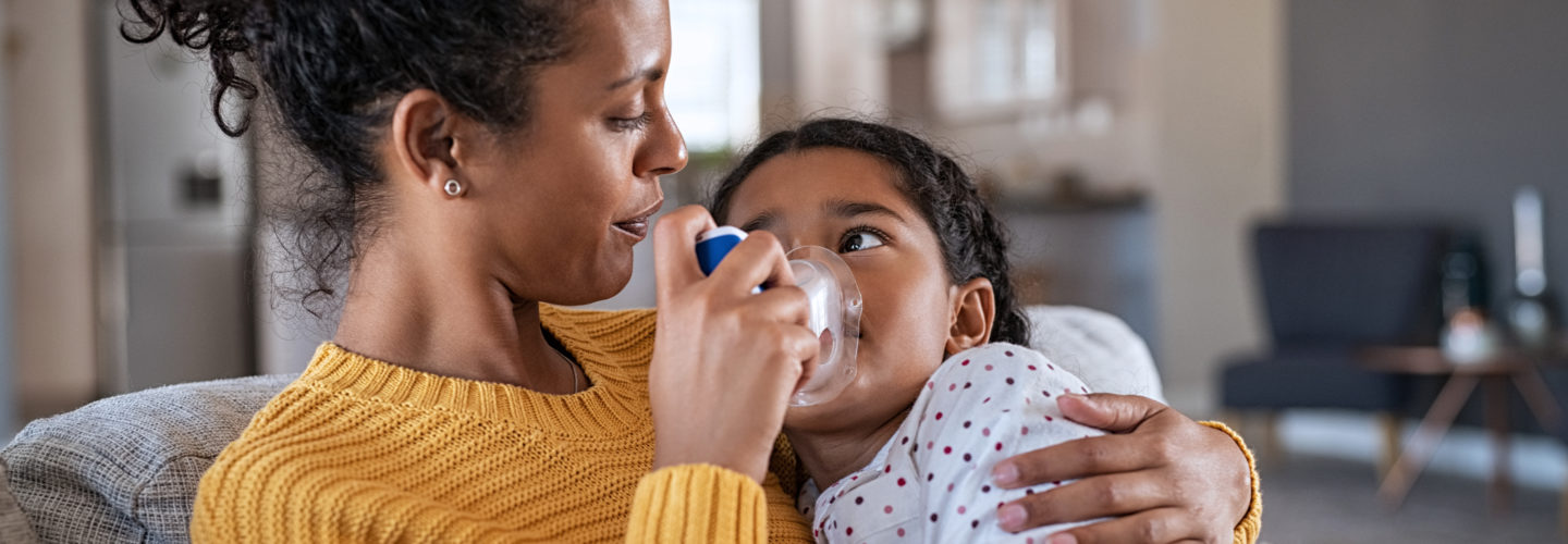 Mother administering inhaler to child