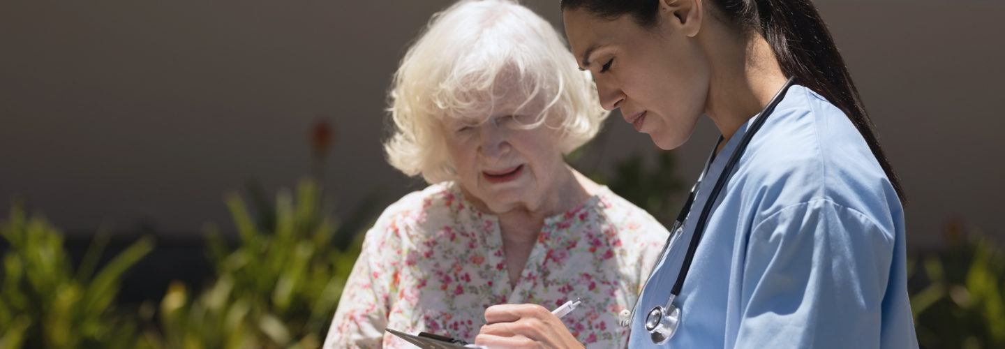 Nurse speaking with elderly woman and writing something down