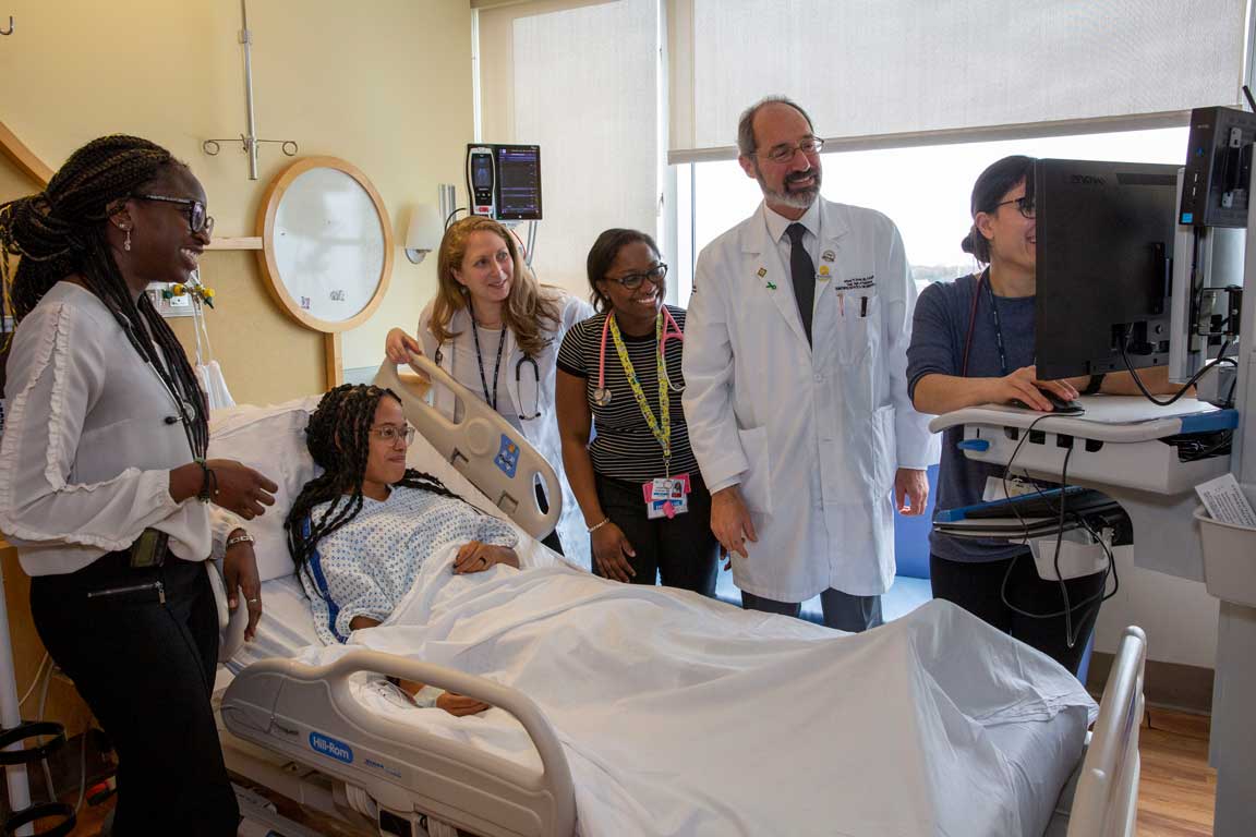 A group of Maimonides doctors and nurses show a patient her improvement on a monitor