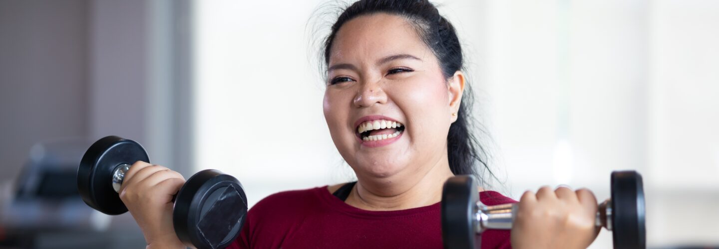 Woman smiling while liftings weights