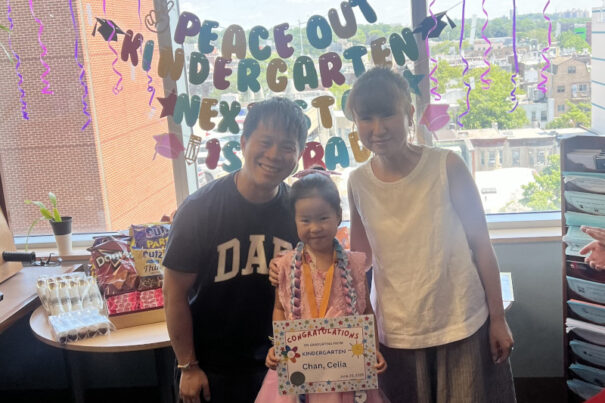 Celia holding graduation certificate and posing with parents