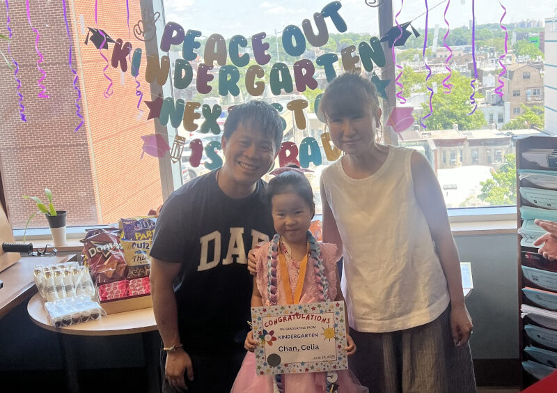 Celia holding graduation certificate and posing with parents