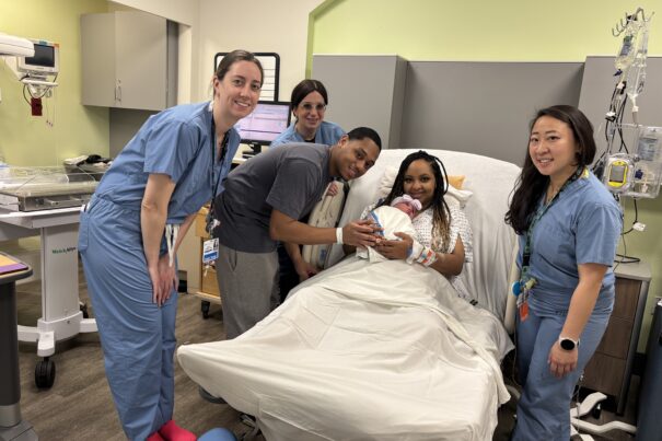 Maternity care team smiling and posing with mother and father and their new baby