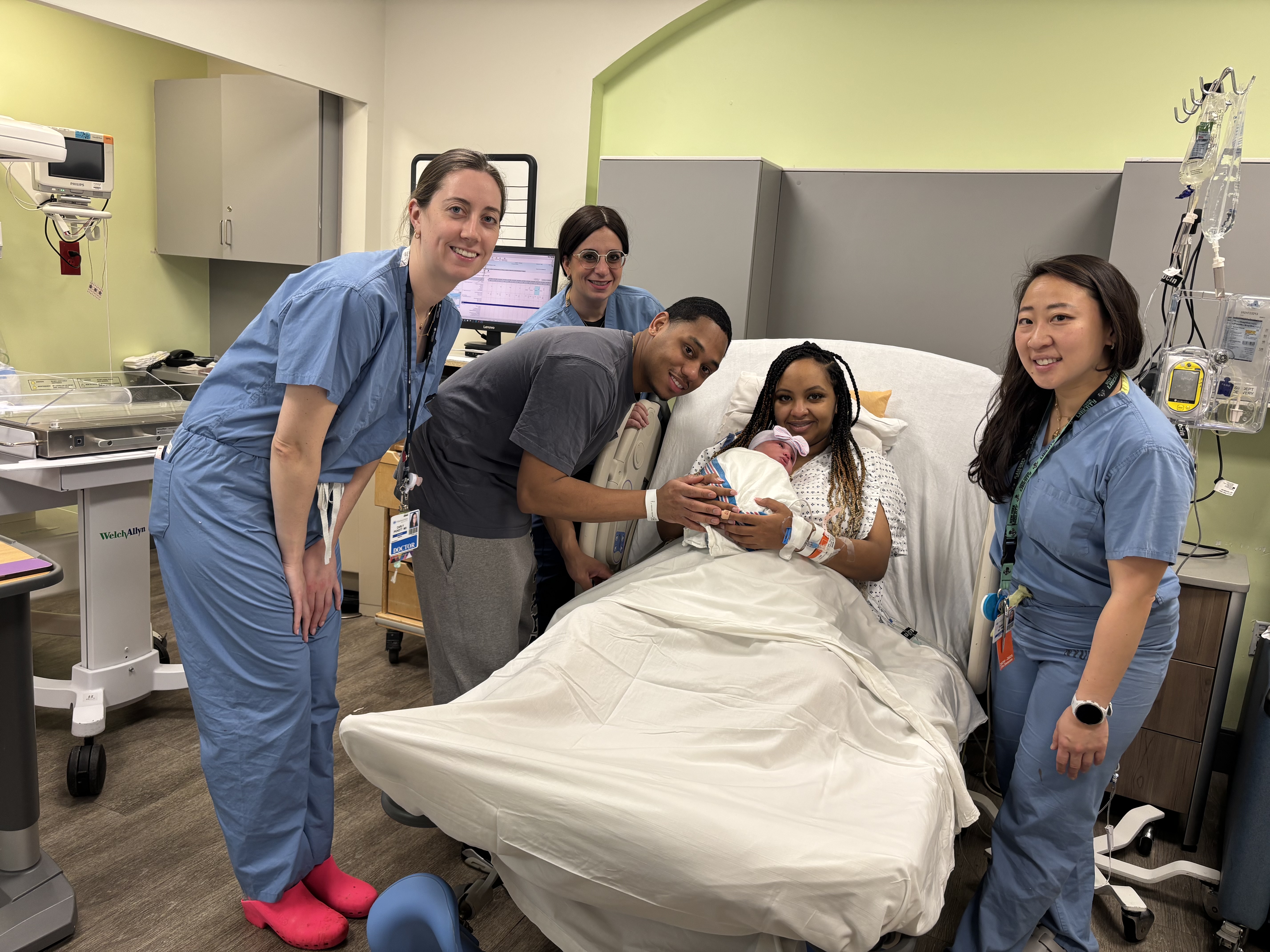 Maternity care team smiling and posing with mother and father and their new baby