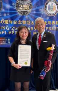 Dr. Mary Lee-Wong smiling and holding her award next to Lester Chang