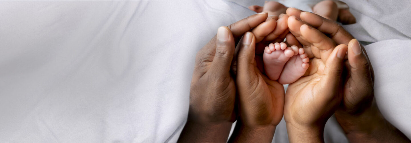 Baby feet held by two sets of overlapping hands