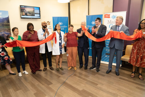 Group of people gathered together to cut a large ribbon